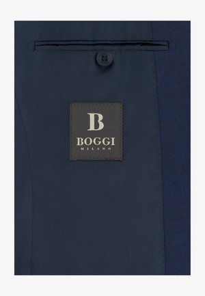 Interior de chaqueta azul oscuro con una etiqueta que dice "B BOGGI MILANO" bajo un único botón y un bolsillo interior horizontal.
