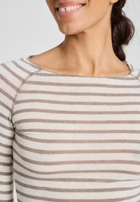 Striped long-sleeve top made from a soft fabric, featuring alternating beige and light brown stripes. Rounded neckline and visible stitching.