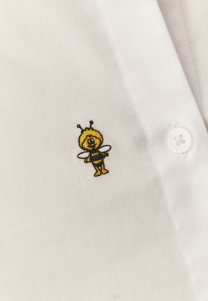 Piccola ape da cartone animato ricamata con strisce nere e gialle, ali e antenne su tessuto di camicia bianca con bottoni.