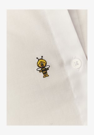 Malá vyšívaná kreslená včela s černými a žlutými pruhy, křídly a tykadly na bílé látce košile s knoflíky.