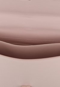 Interno di una borsa a mano in finta pelle rosa con una texture liscia, dotato di un comparto centrale e due tasche laterali. Accenti in hardware dorato.