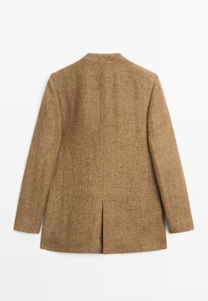 Brun tekstureret blazer med lange ærmer set bagfra, med en central søm og en enkelt slids nederst.