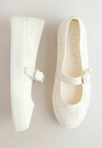 Biele topánky Mary Jane s kvetinovou výšivkou, striebornou prackou na remienku a hrubou bielou gumovou podrážkou, zobrazené zhora a z boku.