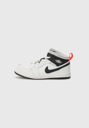 White and black high-top sneaker with a textured leather upper, mesh tongue, black swoosh logo, and bright red accent on the heel.
