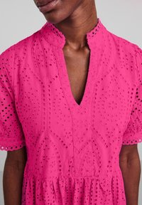 Roze katoenen jurk met een geschulpte kraag en korte pofmouwen. Bevat oogjesdetails en een V-halslijn, met een uitlopende rok.