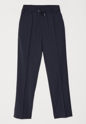 Pantalones azul marino con cintura elástica y cordón. Presentan dos pliegues frontales y perneras ajustadas para una silueta estructurada.