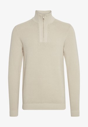 Pull en tricot beige avec un col montant et une fermeture zippée à mi-hauteur. Texture côtelée, manches longues et poignets ajustés. Design épuré et minimal.