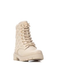 Botas de tobillo beige con cordones, diseño acolchado, herrajes en tono dorado y una suela gruesa y robusta para una mejor tracción.