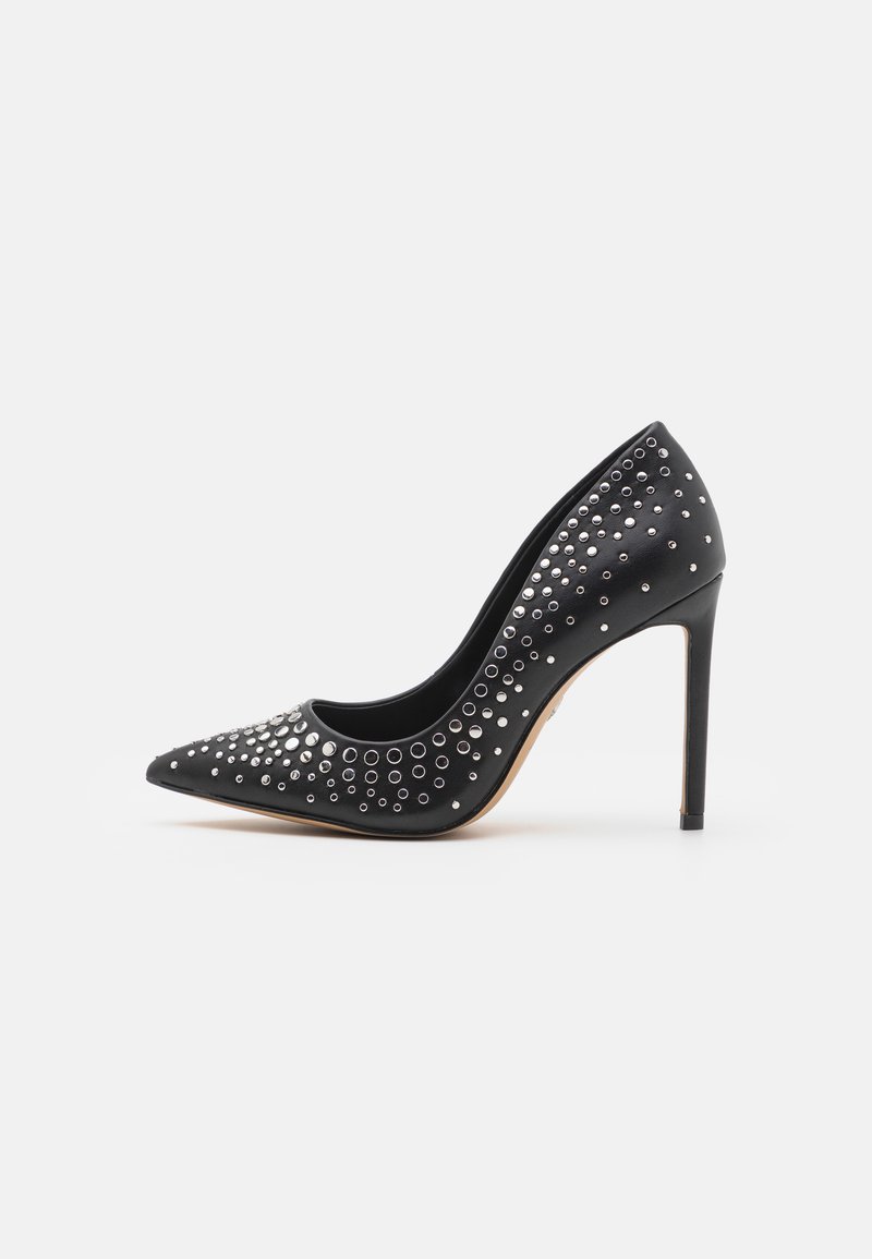 Escarpin noir à talon aiguille avec un bout pointu, orné de clous en argent de tailles variées, texture lisse et talon stiletto.