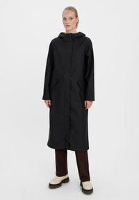 Black waterproof coat with a hood, front snap buttons, side pockets, and elastic drawstrings. Mid-calf length, smooth texture.