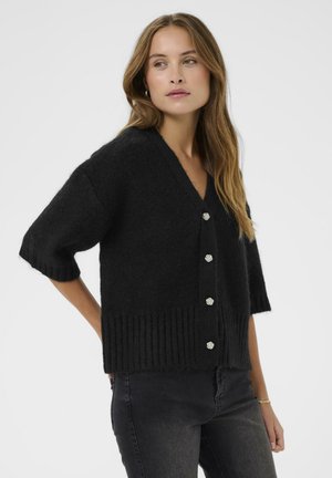 Black knitted cardigan with short sleeves, v-neck, and ribbed hem. Features silver floral buttons down the front for closure.