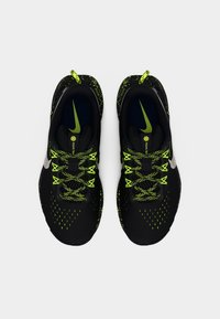 Μαύρα αθλητικά παπούτσια με πράσινες λεπτομέρειες, με άνω μέρος από δίχτυ, υφασμένα μοτίβα και αντανακλαστικό ασημένιο λογότυπο. Τα κορδόνια είναι φωτεινά πράσινα.