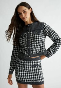 Fekete-fehér hounds tooth mintás dzseki, denim kieg�észítőkkel, patent gombokkal, két elülső zsebbel és cropped fazonnal. Tartalmaz egy illeszkedő szoknyát.