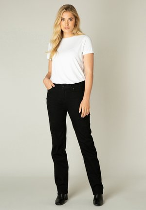 Weißes T-Shirt mit kurzen Ärmeln, kombiniert mit schwarzen Jeans. Schwarze Stiefeletten runden den Look ab. Einfaches, figurschmeichelndes Design ohne Muster.