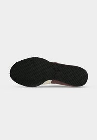 Semelle extérieure en caoutchouc noir d'une chaussure avec un motif antidérapant texturé et un logo Puma au centre, vue de dessous.