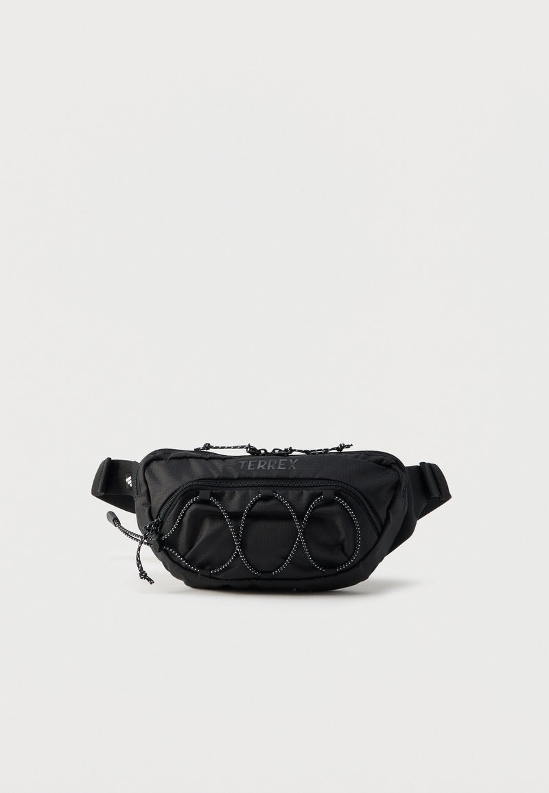 Μαύρο ζώνης τσάντας Terrex με λεπτομέρεια ελαστικού κορδονιού μπροστά, κεντρικά και μπροστινά διαμερίσματα με φερμουάρ και ρυθμιζόμενο λουρί σε απλό φόντο.