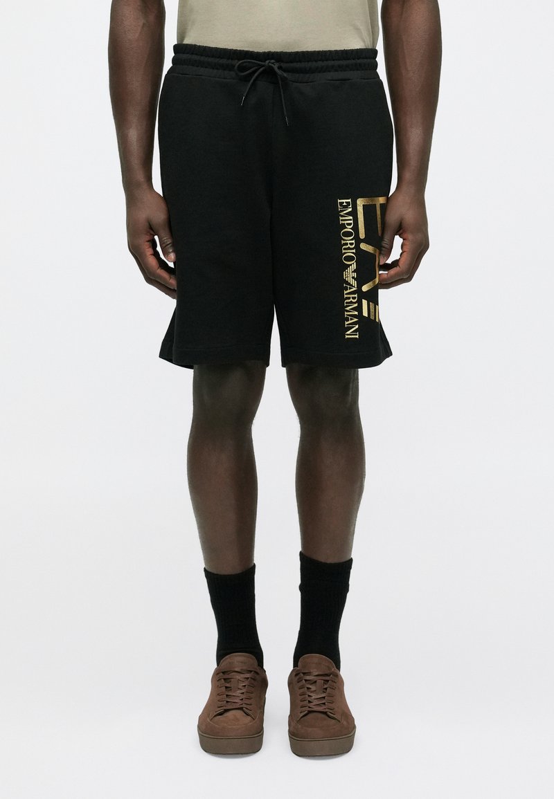 Fekete pamut rövidnadrág gumis derékrésszel és húzózsinórral. Arany "Emporio Armani" logó található a bal oldalon. Laza, hétköznapi kialakítás.