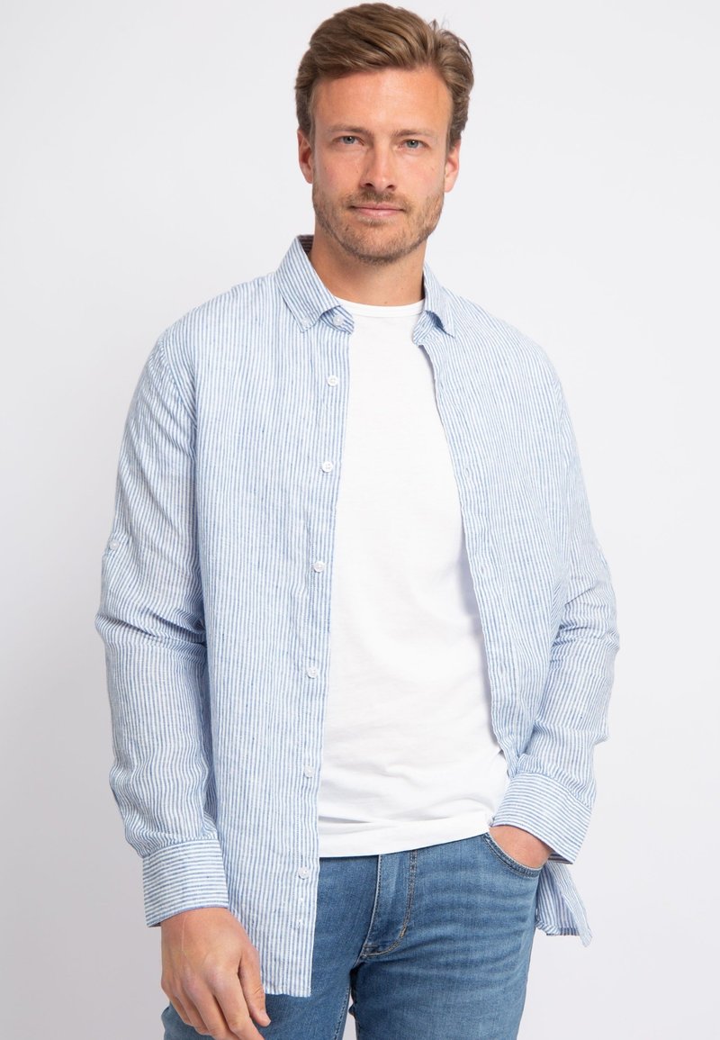 Lichtblauwe en witte gestreepte overhemd met lange mouwen, casual kraag en een wit T-shirt eronder, gecombineerd met blauwe jeans.