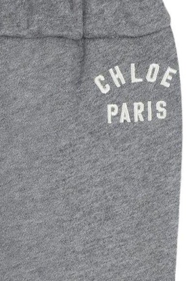 Szare bawełniane dresy mają strukturalne wykończenie z białym napisem "CHLOE PARIS" na boku. Elastyczny pas dla wygody.