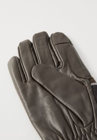 Bruine leren handschoenen met een nauwsluitende pasvorm, voorzien van gestikte details, een gladde textuur en een zachte binnenvoering voor extra warmte.