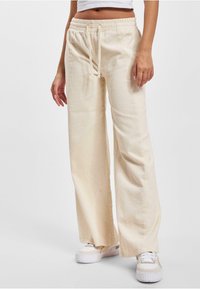 Cremefarbene Cordhose im Weitbein-Design, mit elastischem Bund und Kordelzug. Strukturierter Stoff mit vertikalen Rippdetails.