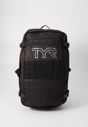 Sac à dos noir avec le logo TYR. Les caractéristiques incluent des sangles réglables, un panneau Velcro à l'avant et une finition en tissu robuste avec des zips.