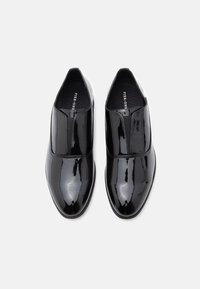 Μαύρα γυαλιστερά παπούτσια slip-on από δέρμα με ομαλή επιφάνεια, ελαστικές πλαϊνές επιφάνειες και στρογγυλεμένο σχέδιο μύτης. Το εσωτερικό διαθέτει μαύρη υφασμάτινη επένδυση.