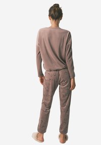 Blødt, gråbrunt loungewear sæt med langærmet top og mønstrede bukser. Sweateren har en afslappet pasform; bukserne har et subtilt print.