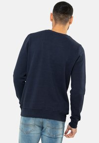 Marineblauwe sweatshirt met lange mouwen, gemaakt van zachte stof. Heeft een ronde halslijn en ribgebreide manchetten en zoom. Achteraanzicht weergegeven.