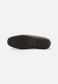 Zwarte sneakerzool met een getextureerde rubberen loop. Heeft een minimalistisch ontwerp en een gladde bovenkant. Bevat een ronde logo-afdruk.