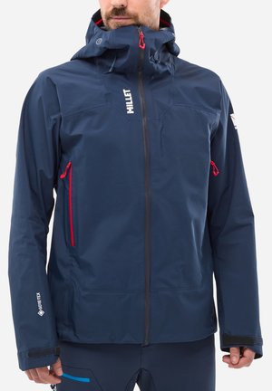 Navy blue waterproof jacket with red accents, a high collar, adjustable hood, and two zippered pockets. Features a GORE-TEX logo on the sleeve.