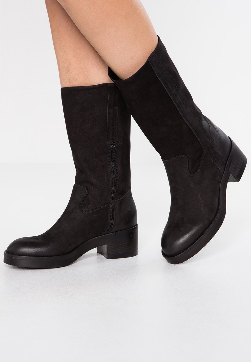 Czarne zamszowe botki do kolan z okrągłym noskiem, blokowym obcasem i zamkiem bocznym. Gładka struktura z minimalnymi akcentami i elegancki design.
