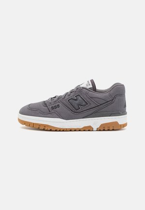 Baskets New Balance 550 grises avec logo noir, semelle intermédiaire blanche et semelle extérieure en caoutchouc naturel, présentées de profil sur fond blanc.