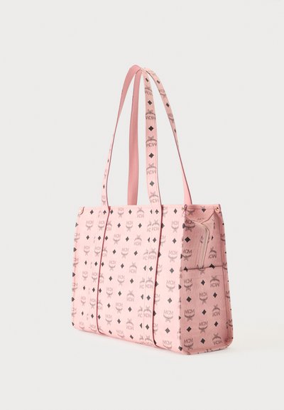 Sac cabas rose avec logos MCM noirs et motifs en diamant, doté de deux bretelles et d'une poche latérale zippée.