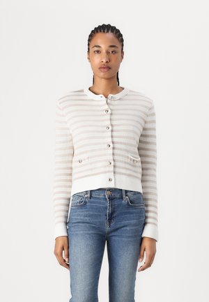 Cardigan court léger en crème avec des rayures beiges, fermeture à boutons, col rond et deux petites poches avant. Tricot doux et texturé.