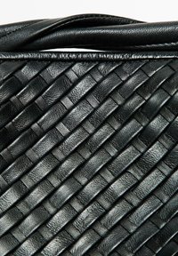 Borsa a mano in pelle nera intrecciata con superficie testurizzata caratterizzata da un motivo di strisce intrecciate e una parte superiore liscia.