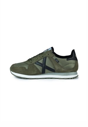 Olive green sneaker featuring a combination of suede and mesh, black accents, textured surface, and a rubber sole with a white midsole.