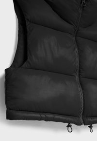 Black quilted sleeveless vest with front zipper and adjustable drawcords at the bottom hem against a white background.