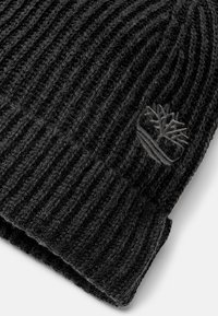 Czarna dziana czapka z prążkowanym wzorem. Ozdobiona subtelnym haftowanym logo. Wykonana z miękkiego materiału, idealna do zapewnienia ciepła i komfortu.