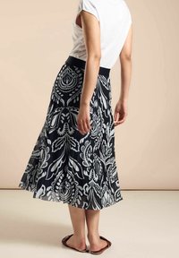 Czarna i biała spódnica w kwiatowy wzór z plisowanym fasonem, wyposażona w szeroką elastyczną talię i luźny krój.