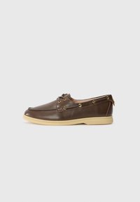 Brown leather boat shoe with a rounded toe, gold eyelets, and a tan rubber sole, featuring laces and minimal decorative stitching.