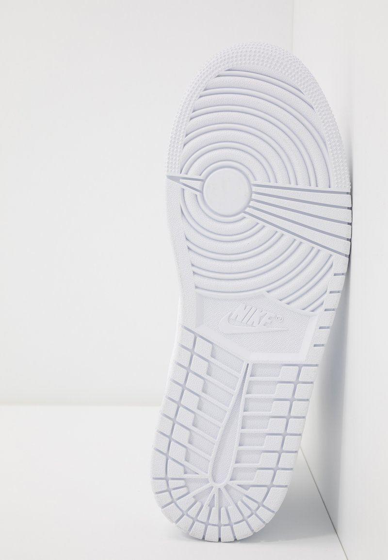 Semelle de sneaker blanche avec des motifs de bande de roulement circulaires et linéaires, surface texturée et logo visible. Design minimaliste et finition lisse.