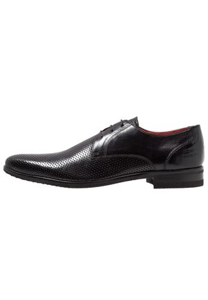 Zapato de vestir para hombre de cuero negro con diseño perforado, cierre de cordones y tacón bajo, mostrado desde vista lateral sobre fondo blanco.