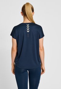 Marinblå idrottströja med korta ärmar, som har ett vertikalt chevronmönster i en ljusare nyans på baksidan. Slät textur, avslappnad passform.