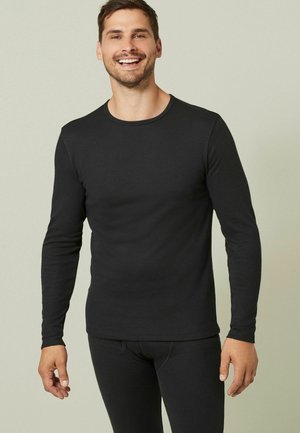 Schwarzes Langarmshirt mit Rundhalsausschnitt, aus geripptem Stoff gefertigt. Es hat eine taillierte Passform und wird mit passenden schwarzen Unterteilen kombiniert.