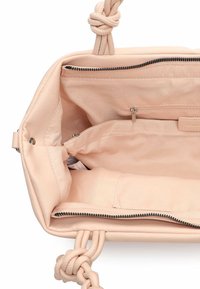 Interno di borsa in pelle sintetica rosa con manici intrecciati a nodo, dotata di diverse tasche e un compartimento con cerniera. Texture liscia.