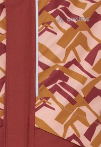 Tecido laranja e marrom com padrões geométricos. Apresenta um destaque cinza vertical e uma etiqueta de marca no canto. Textura suave.