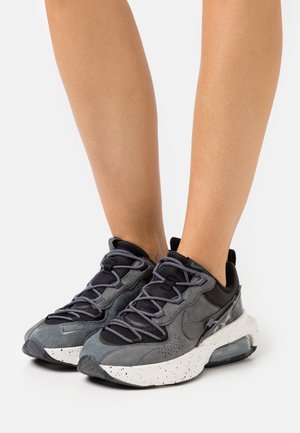 Gray sneakers with a mix of suede and mesh, featuring a speckled white sole, black accents, and a prominent lacing system.