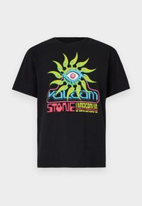 Camiseta de algodón negra con un diseño gráfico multicolor que presenta un ojo central y rayos similares al sol, mostrando elementos de texto en negrita debajo.