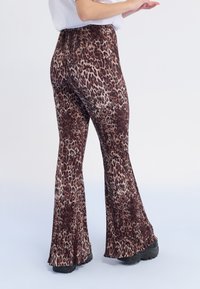 Leopardmönstrade utsvängda byxor i en texturerad fabric, med hög midja och vida ben, främst i brun och beige nyanser.